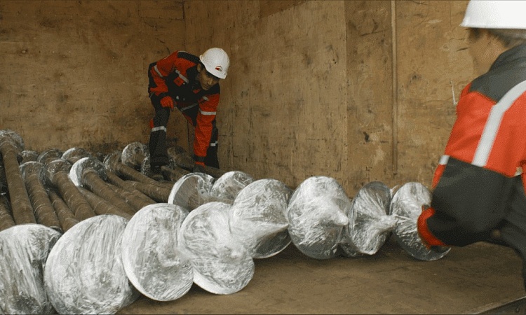 Строительство фундамента начинается с подвоза и выгрузки на участке винтовых свай.